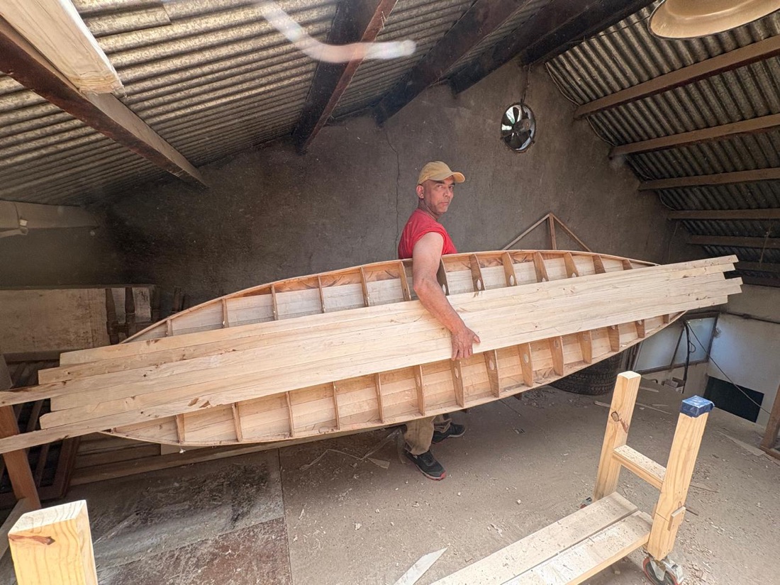 El carpintero de Arte y Oficio construyendo una canoa de madera en el taller